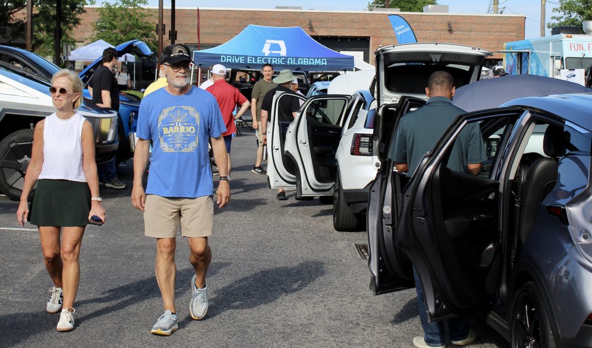 Attendees browse electric vehicles on display at a Drive Electric Alabama outdoor show event in Birmingham