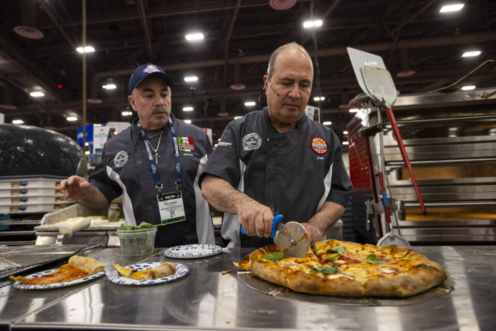 Metro Pizza co-owner John Arena, right, speaks during a demonstration at the Marra Forni Brick ...