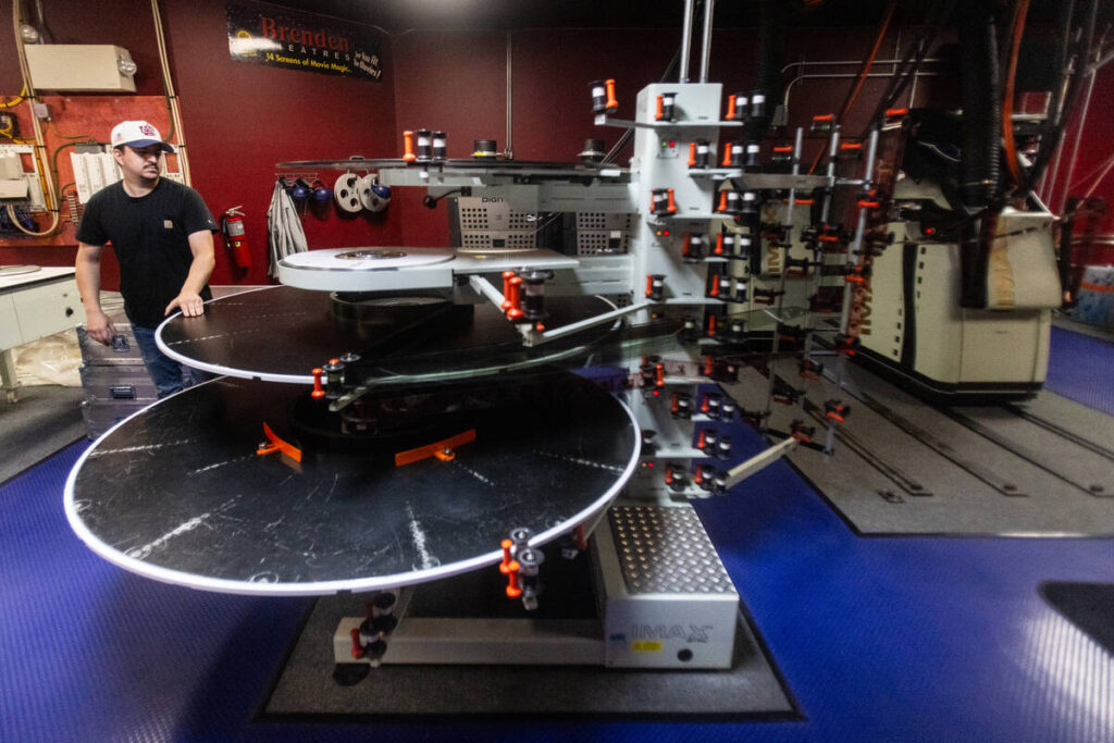 Shane Kaiser, a region technician at Brenden Theaters,“threads up” film for an IMAX project ...