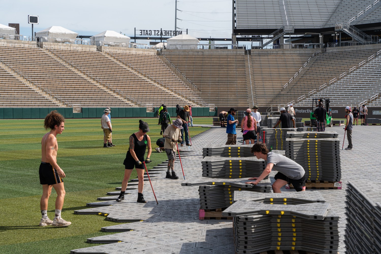 Production crew members install protective floor panels over the turf at Protective Stadium ahead of The RB Tour concert