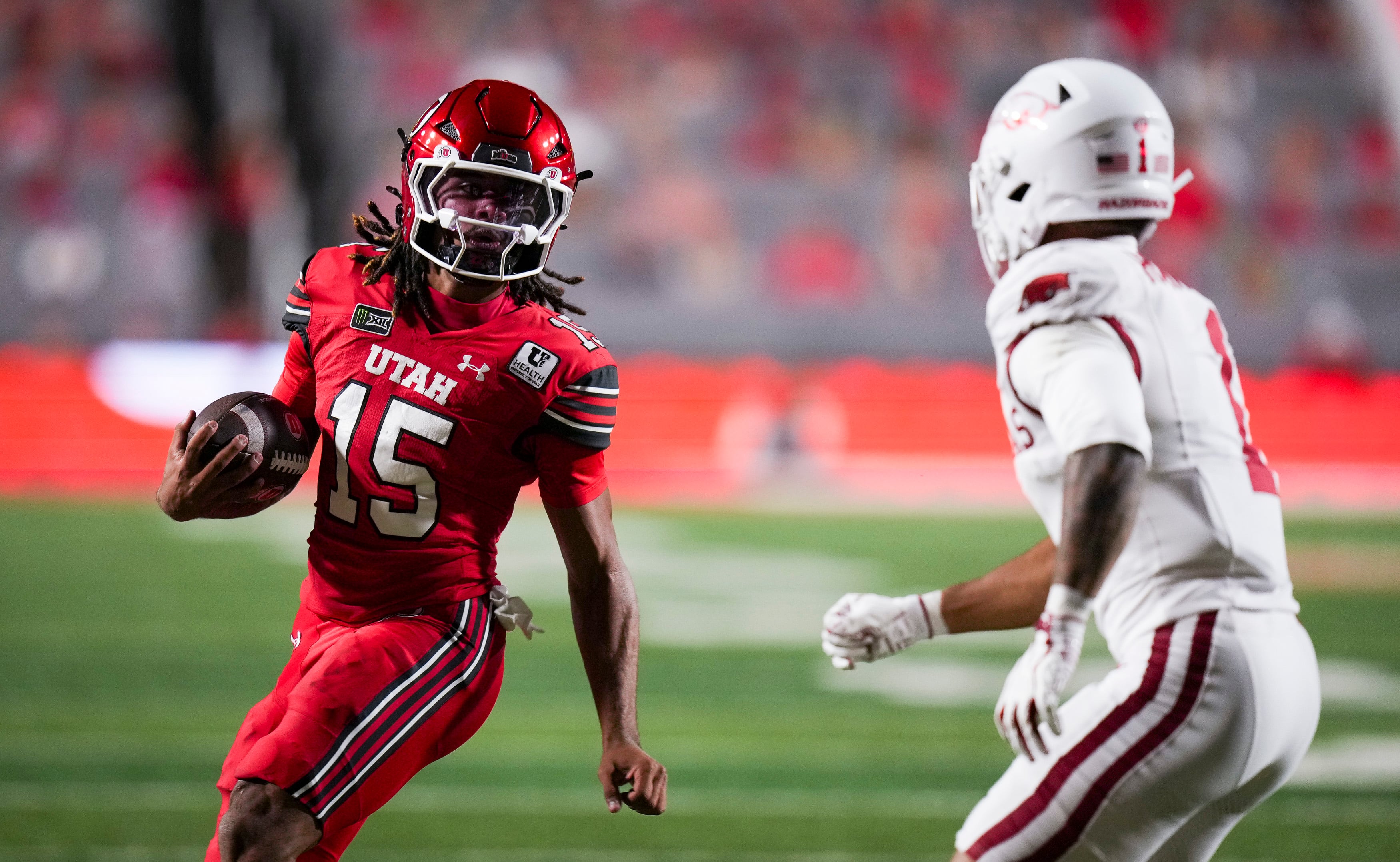 (Bethany Baker  |  The Salt Lake Tribune) Utah Utes quarterback Byrd Ficklin (15) avoids a tackle from Arkansas Razorbacks defensive back Christian Harrison (1) during the game between the Utah Utes and the Arkansas Razorbacks in Salt Lake City on Saturday, Sept. 12, 2026.