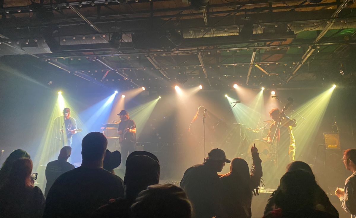 A band called Winston Ramble is playing live on stage to a crowd of fans at Saturn bar in Birmingham, Alabama.