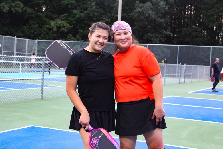 Two women standing on a pickleball court