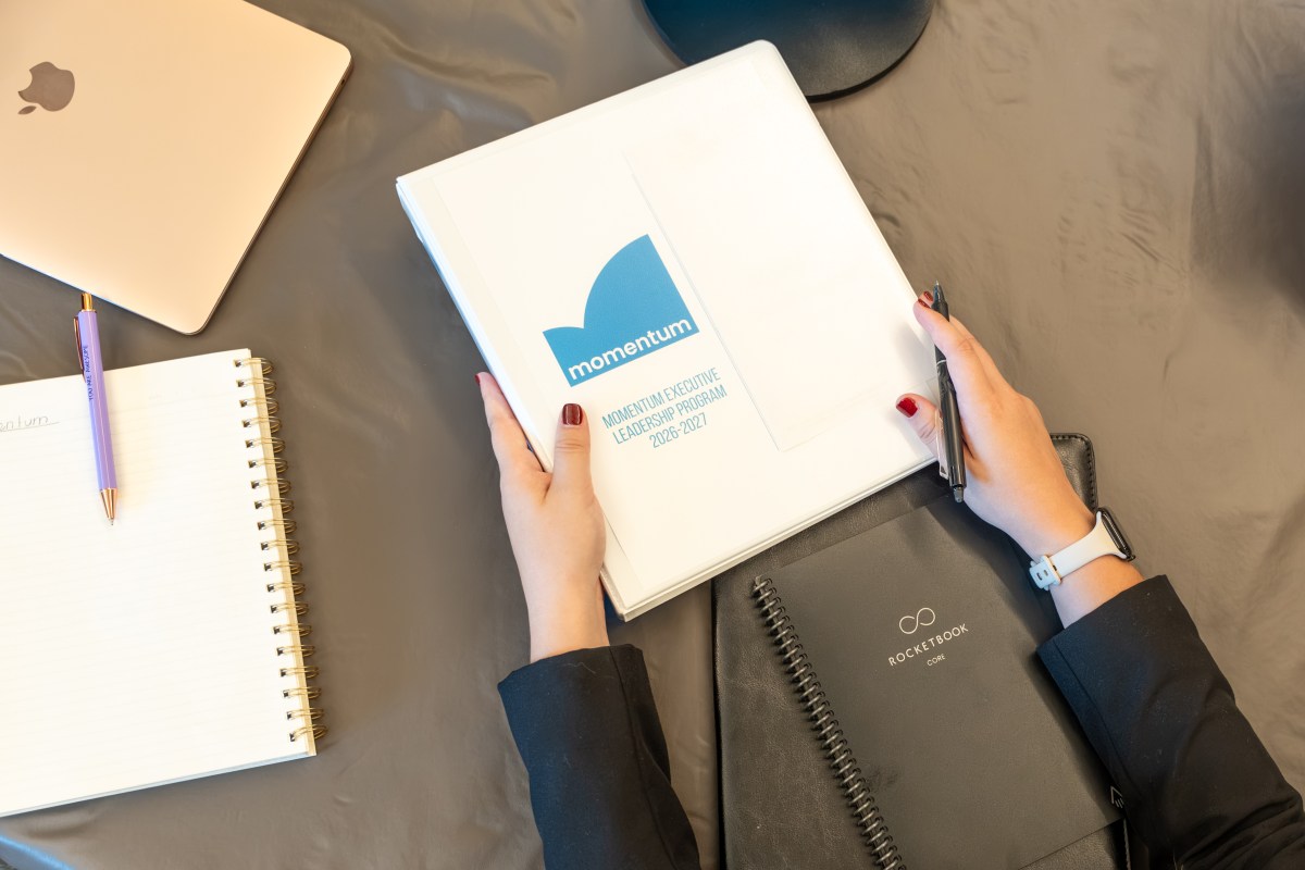 hands holding a binder with Momentum Leaders logo on it