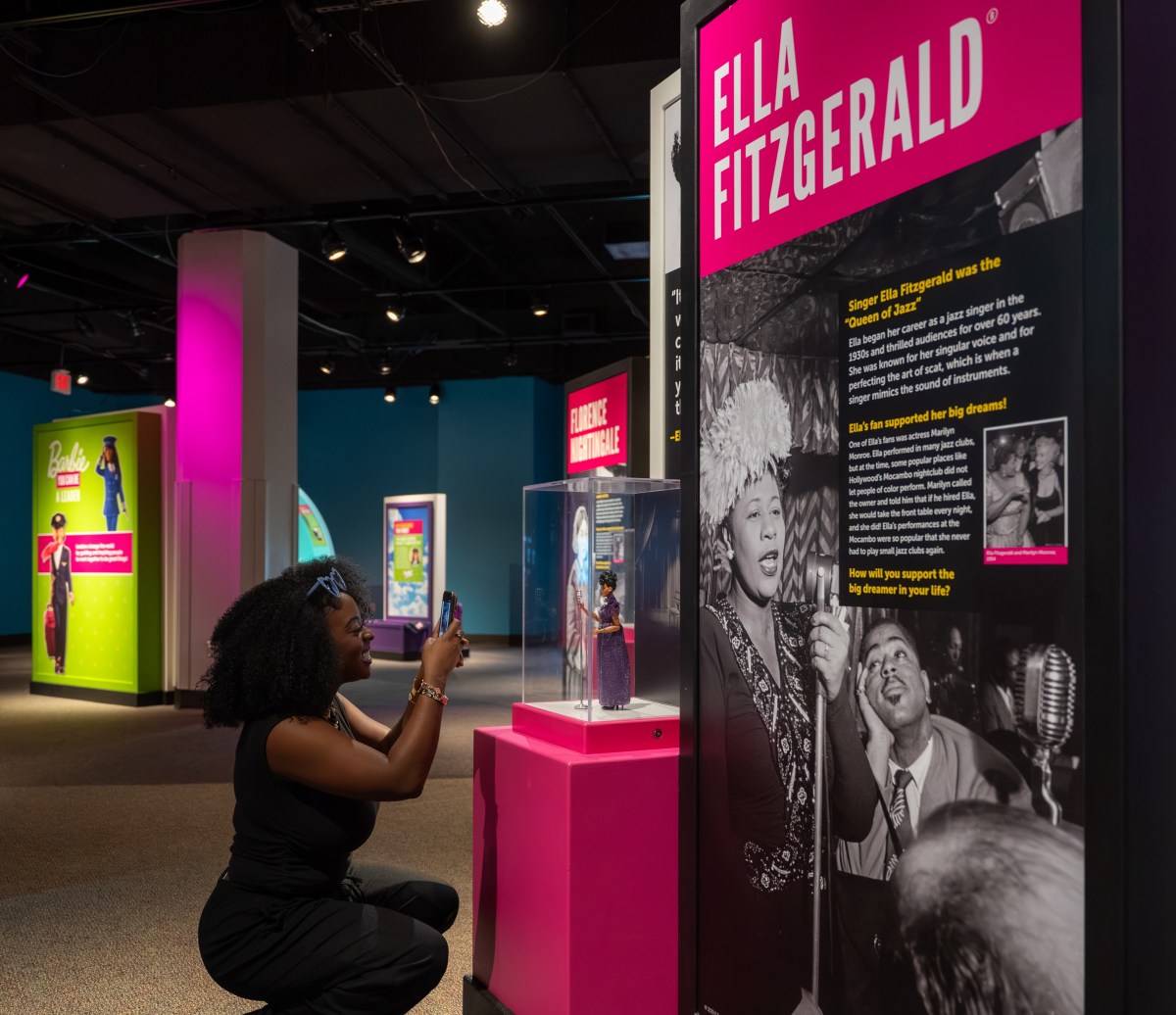 A visitor photographs the Ella Fitzgerald Barbie doll display, part of the exhibit's role model section on career dolls