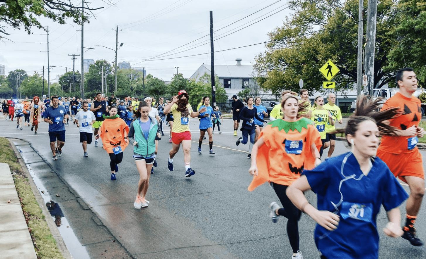32 family-friendly Halloween events in Birmingham 8 Runners in Halloween costumes, including pumpkin outfits, race down a city street with numbered bibs
