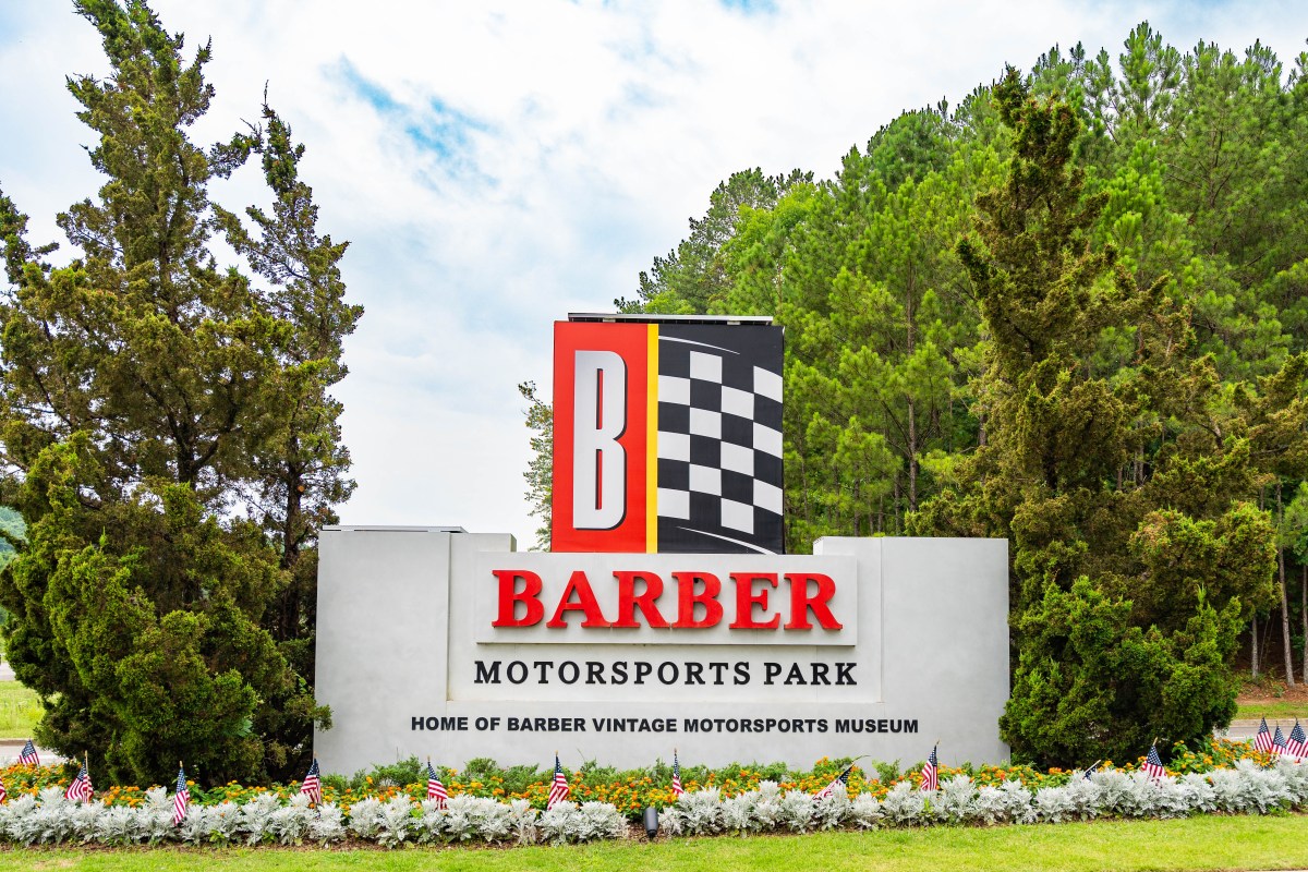 Entrance sign for Barber Motorsports Park, Home of Barber Vintage Motorsports Museum, with American flags lining the flower bed below